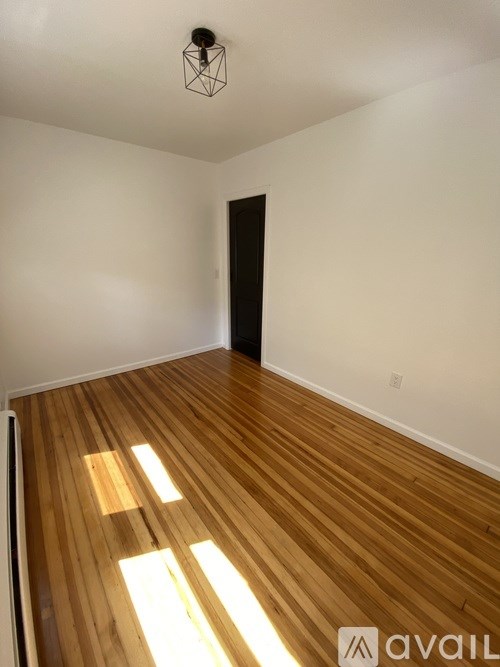 A room with wooden flooring and a black door.