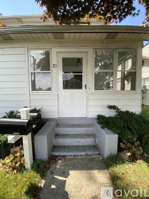 A white house with a black mailbox and steps leading to the door.