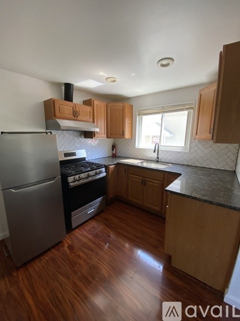 A kitchen with wooden cabinets and a black and white tiled backsplash.