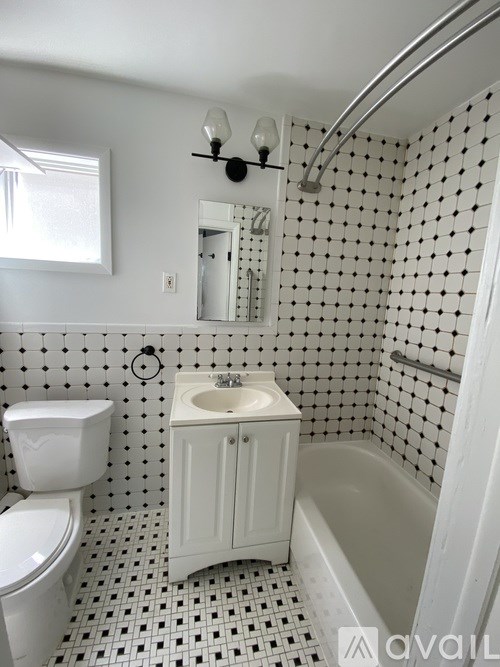 A white toilet sits next to a sink in a bathroom with black and white tiles.
