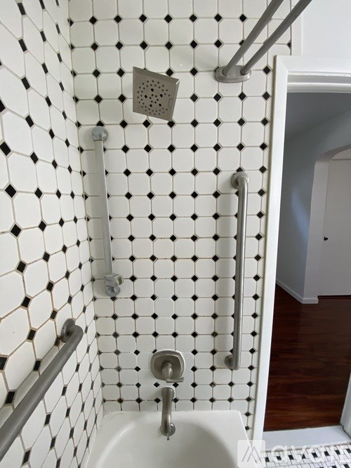 A white tiled shower with a white tub and silver fixtures.