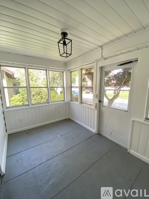 A sunny room with a white ceiling and a door.
