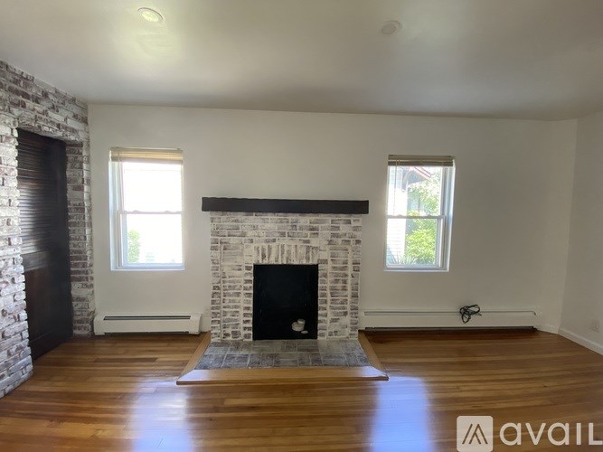 A room with a stone fireplace and wooden floors.