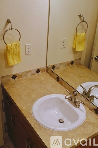 A bathroom with a sink, mirror, and towel rings.
