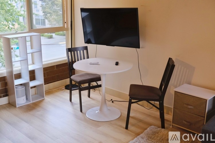 A black screen on a white table with a black chair and a white shelf with three bins.
