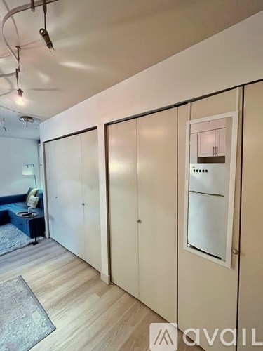 A room with a white wall and a fridge built into it.
