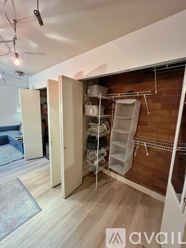 A room with a white door open to a closet with clothes hanging.