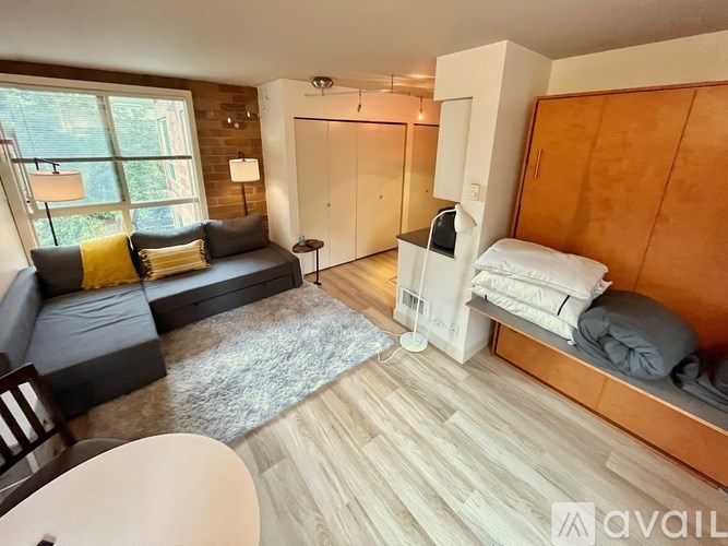 A living room with a grey couch and a white bed.