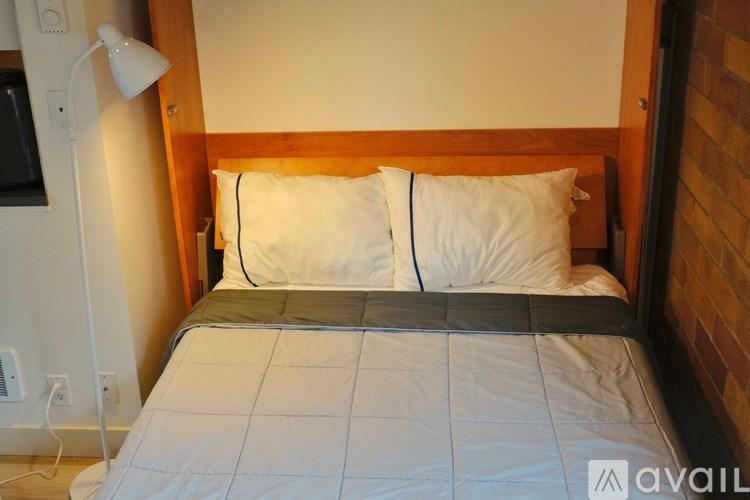 A bed with a white comforter and two pillows with a wooden headboard.
