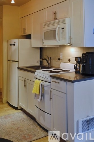 A kitchen with white appliances and a black counter.