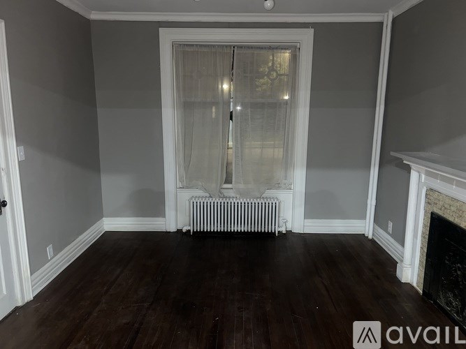 A room with a fireplace and a window with curtains.