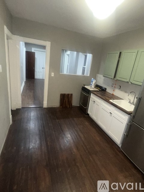 A kitchen with white appliances and green cabinets.