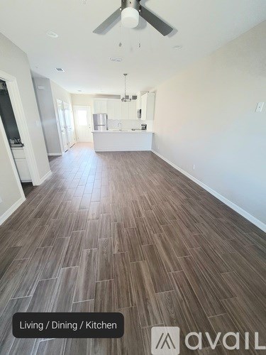 A spacious living, dining, and kitchen area with wood flooring.