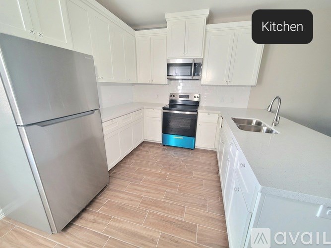 A kitchen with a refrigerator, microwave, oven, and sink.