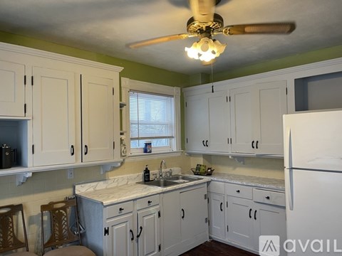 A kitchen with white cabinets and a ceiling fan.