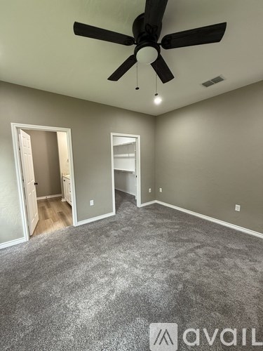 A room with a ceiling fan and carpeted floor.