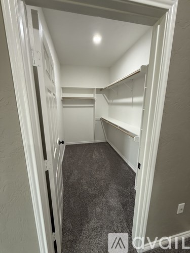A small, empty walk-in closet with white shelves and a carpeted floor.