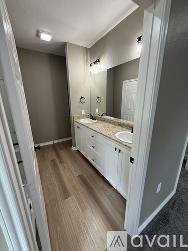 A bathroom with a sink, mirror, and wooden floors.