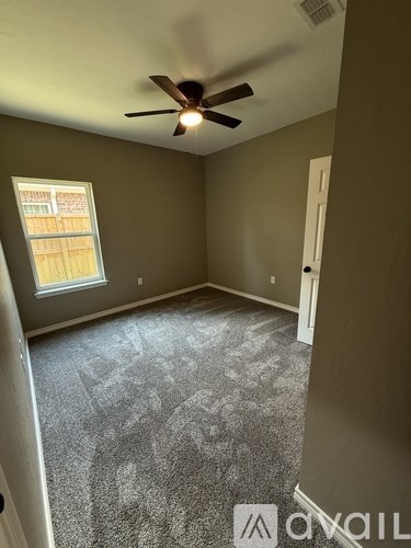 A room with a ceiling fan and carpeted floor.