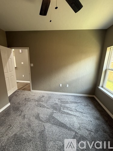 A room with a grey carpet and a ceiling fan.