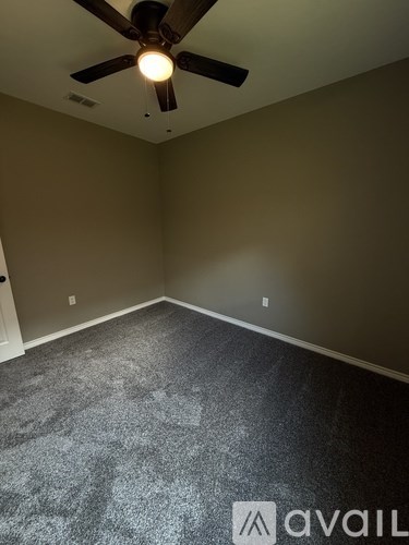 A room with a ceiling fan and carpeted floor.
