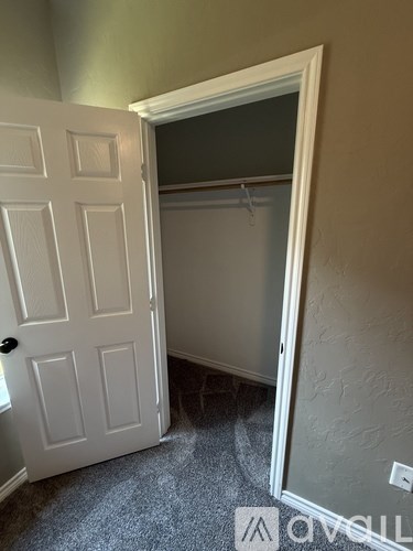 A white door is open to a room with a grey carpet.