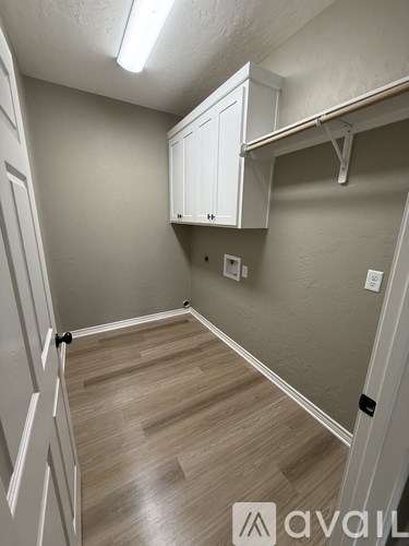 A room with a white cabinet and wooden flooring.