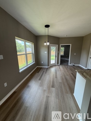 A room with wooden flooring and a large window.