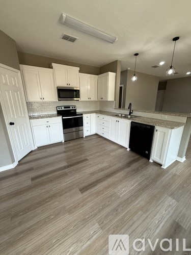 A kitchen with white cabinets and a wooden floor.