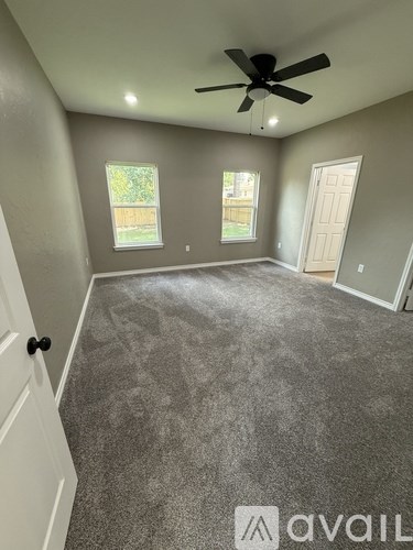 A room with a ceiling fan and two windows.
