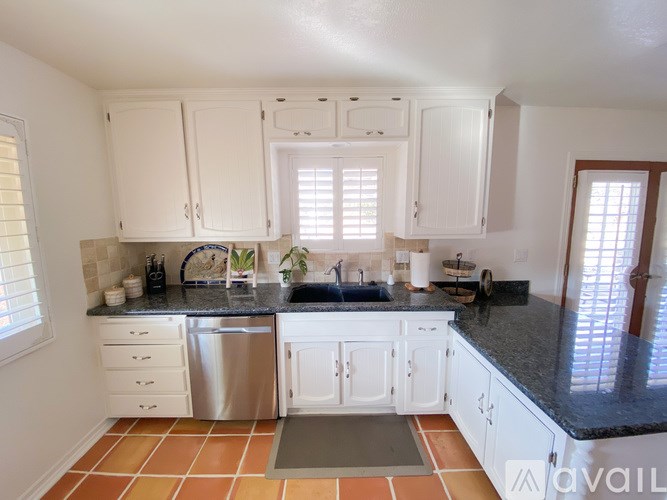 A kitchen with white cabinets and a black countertop.