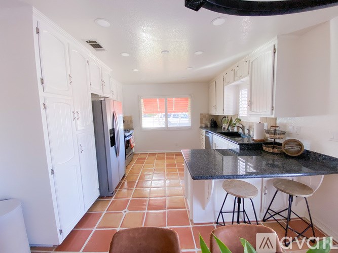 A kitchen with a black counter top and white cabinets.