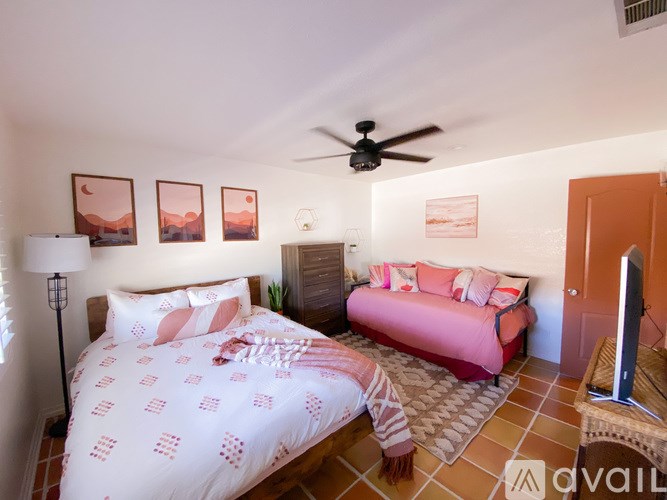 A bedroom with a bed, a couch, and a ceiling fan.