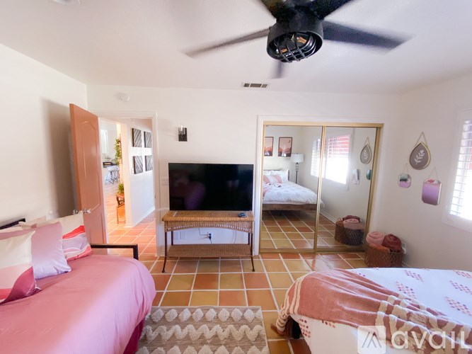 A bedroom with a bed, a television, and a ceiling fan.