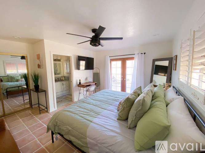 A bedroom with a large bed and a ceiling fan.