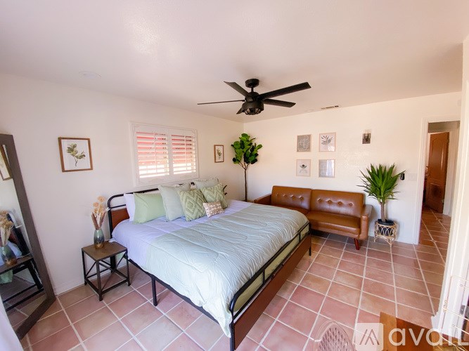 A bedroom with a bed, a bench, and a ceiling fan.