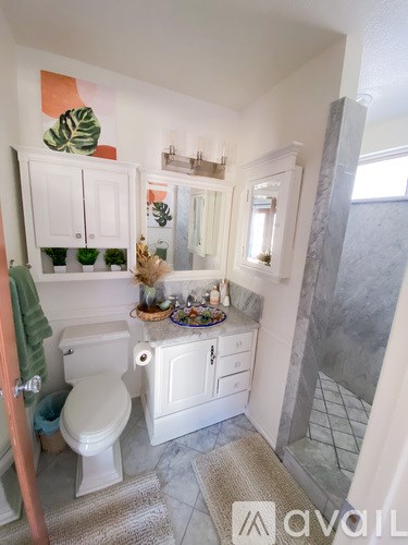 A bathroom with a toilet, sink, and cabinets.