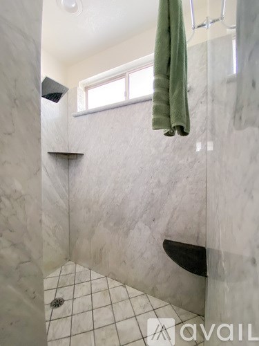 A bathroom with a green towel hanging on the shower rod.
