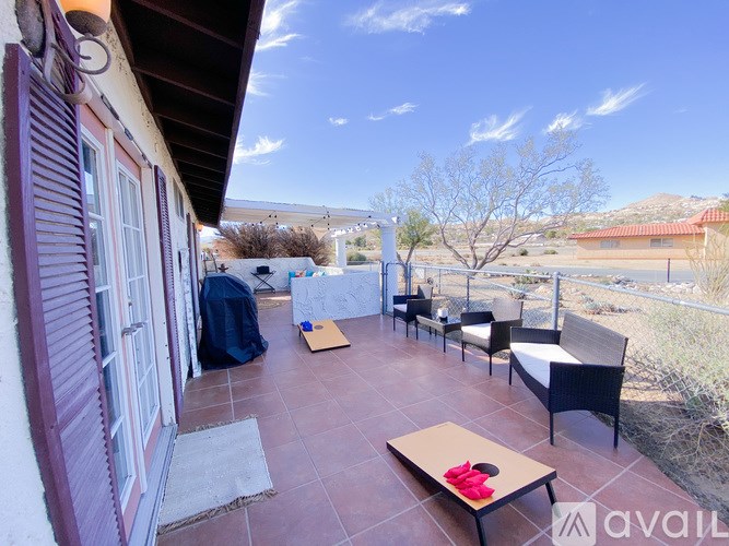 A balcony with a table and chairs overlooking a desert landscape.