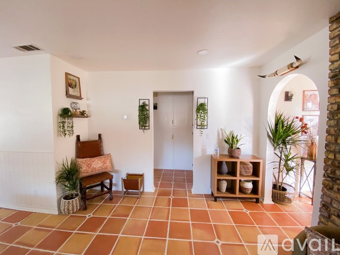 A living room with a bench, potted plants, and a fireplace.