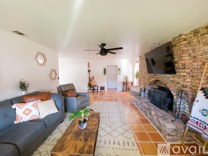 A living room with a grey couch, a wooden coffee table, and a brick fireplace.