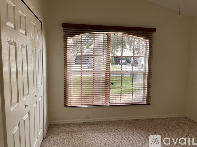A room with a window covered by blinds and a car parked outside.