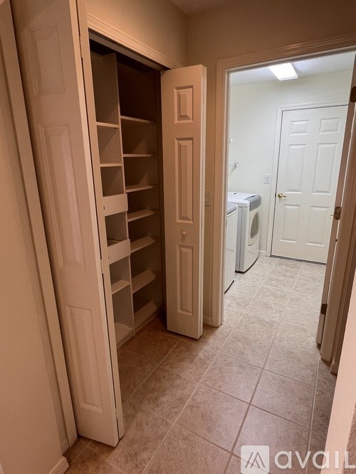 A white pantry with a dryer in the background.