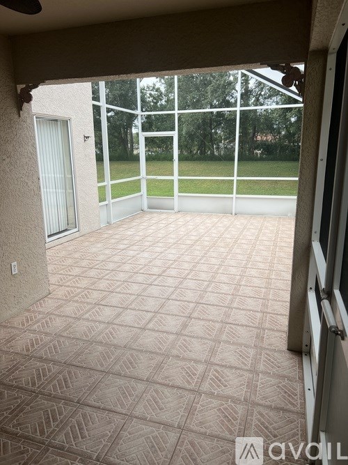 A patio with a tiled floor and a sliding glass door leading to a grassy area.
