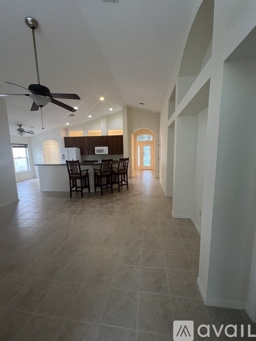 A spacious dining room with a table set for six and a fan on the ceiling.