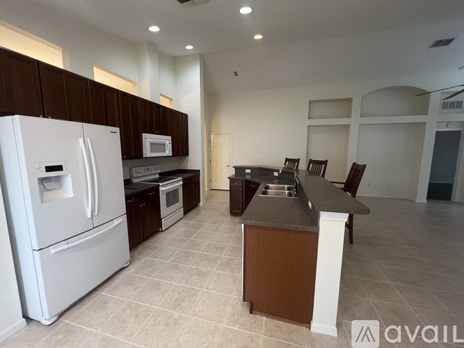 A kitchen with a white refrigerator and brown cabinets.