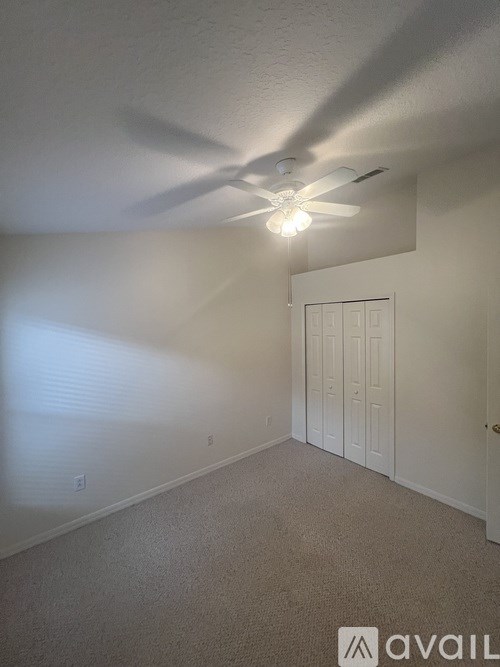 A room with a ceiling fan and a door.