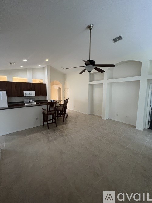 A spacious room with a ceiling fan and a bar area.