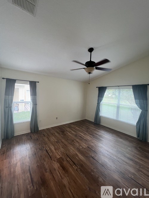 A room with a ceiling fan and wooden flooring.