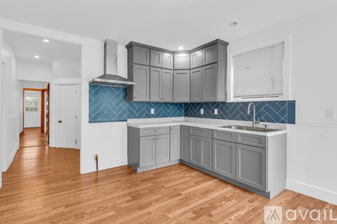 A kitchen with wooden floors and a blue backsplash.
